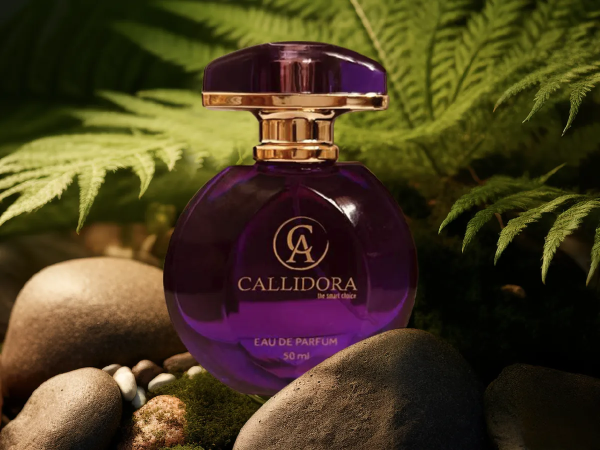 Flacon de parfum Callidora violet posé parmi les fougères et les galets