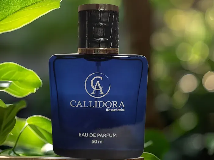 Flacon de parfum Callidora bleu posé dans la verdure au soleil